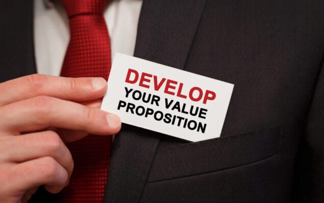 Businessman putting a card with text Develop Your Value Proposition in the pocket